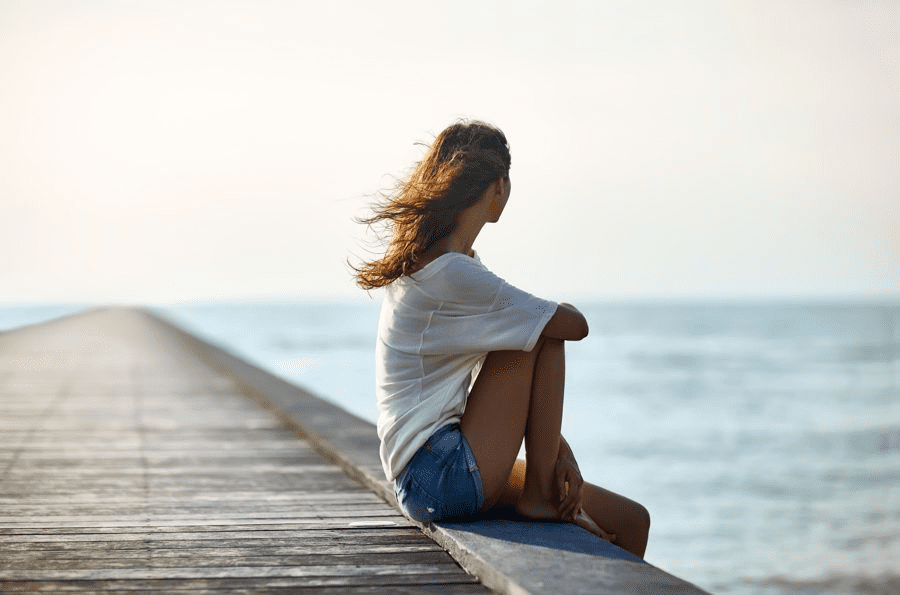 a girl sitting alone on a shore deck