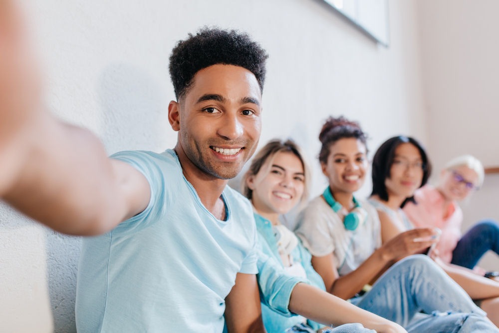 a teen guy taking a selfie photo with his friends