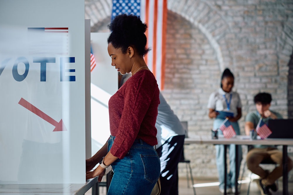 A woman stands confidently in front of a voting booth, ready to cast her vote in an important election.